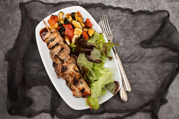 Grilled meat on stick with spices, vegetables and fresh salad