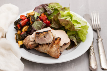 Baked pork with vegetables and fresh salad on plate