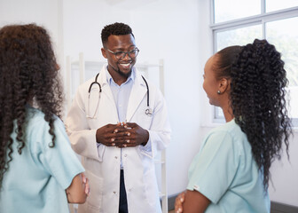 Senior doctor listens to junior healthcare assistant, standing in hospital