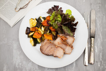 Baked pork with vegetables and fresh salad on plate
