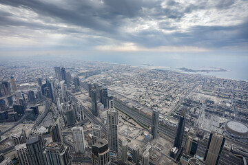 Fototapeta na wymiar Dubai from above. Aerial view from Burj Khalifa skyscraper tower to city of Dubai during a cloudy day. United Arab Emirates, 2023.