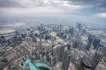 Dubai from above. Aerial view from Burj Khalifa skyscraper tower to city of Dubai during a cloudy day. United Arab Emirates, 2023.