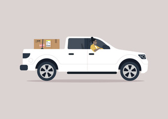 A young driver of a pickup truck driving with one elbow hanging out of the window, a cardboard box in the trunk