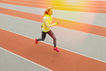 Top view of an athlete running on a treadmill. A young woman in a bright tracksuit. Competitions.Photo with toning