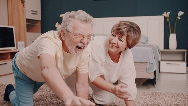  Husband and wife. Yoga. Good mood.  A very nice elderly couple are doing gymnastics and laughing. Real emotions. Cute happy family. Love for life. Grandma and grandpa. The story of one big  family.