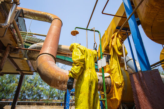 Male workers dressing in protective shower detoxification suit clean up after sealing a leaking container from corrosive toxic