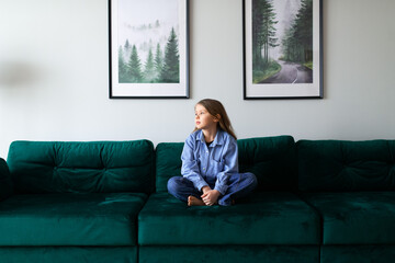Obraz premium portrait of a schoolgirl in blue shirt sitting on sofa at home