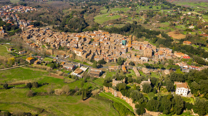 Fototapeta na wymiar Aerial view of the historic center of Sutri, near Viterbo and Rome, Italy. The Romanesque cathedral with its bell tower dominates the city. All houses have traditional red tiled roofs in the old town.
