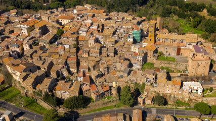 Obraz premium Aerial view of the historic center of Sutri, near Viterbo and Rome, Italy. The Romanesque cathedral with its bell tower dominates the city. All houses have traditional red tiled roofs in the old town.