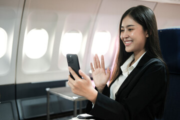 Obraz premium Asian female using smartphone and modern laptop computer while sitting in airplane, Sun rise from the window of an airplane seat, Traveling and technology concept.