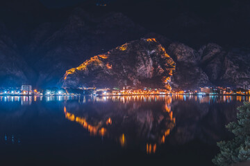 Beautiful night landscape. City in Montenegro Kotor with an old fortress reflected in the bay. Adriatic Sea and travel to the Balkans