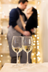 Silhouette of a couple in love in the background and two glasses of champagne in the foreground 