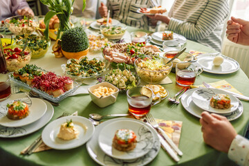 Home interior with easter decor. Spring flowers in a vases. Traditional Easter dishes with white borscht, sausage, eggs, salad and cakes on festive table in Poland