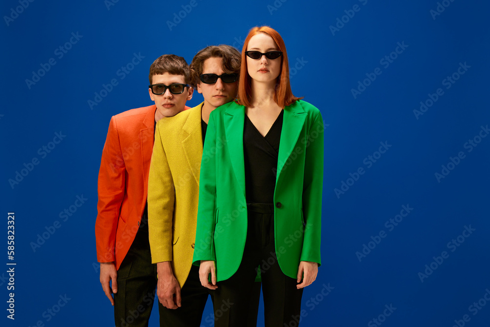 Sticker Men and woman wearing colorful jackets and dark sunglasses standing with calm face over blue background