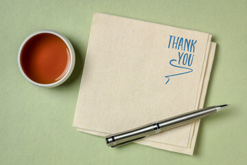 Thank you phrase - handwriting on a napkin with a cup of tea with a copy space