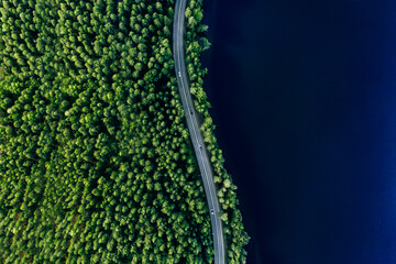 Aerial view of road in green woods and blue lakes water in Finland - Powered by Adobe