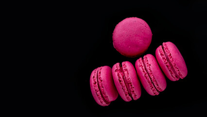 Pink macaroons on a black background. Place for text.