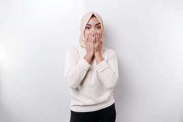 Portrait of a young Asian Muslim woman wearing a headscarf is tell be quiet, shushing with serious...