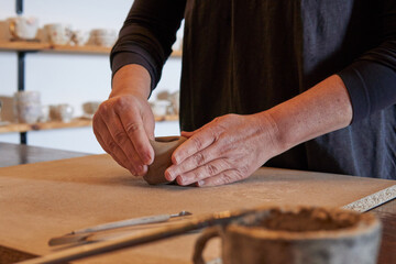 Craftswoman sculpting artistic cups and pots out of clay, handcrafted in a studio, handmade molding process, pottery