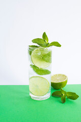 Mojito cocktail in the drinking glass on the colored background. Close-up.