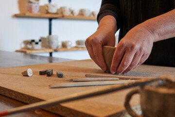 Craftswoman sculpting artistic cups and pots out of clay, handcrafted in a studio, handmade molding process, pottery