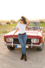 beautiful girl in retro style posing near vintage red cabriolet car.