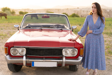 beautiful girl in retro style posing near vintage red cabriolet car.