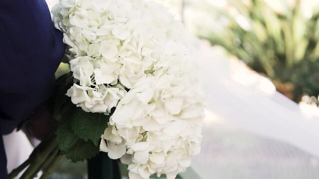 Slow motion shot of a white bouquet of flowers and the bride's veil floating in the wind