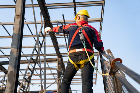 Working at height equipment. Fall arrestor device for worker with hooks for safety body harness on selective focus. Worker as a background.