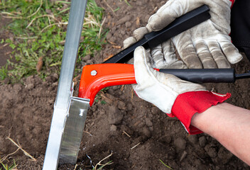 Close up view of man hand use rivet gun to install greenhouse metal construction, attach with...