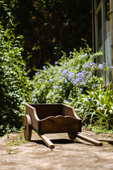 Little wooden pushcraft in garden in front of green leaves