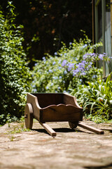Little wooden pushcraft in garden in front of green leaves