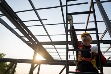 Fototapeta premium Asian worker wear safety height equipment to install the roof. Fall arrestor device for worker with hooks for safety body harness, Worker as in the construction site