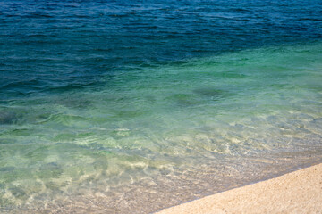 Marine background, blue and turquoise water in a gradient on the surface of the sea, sandy beach