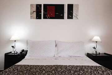 Hotel bedroom with white and black bed and painting on the wall
