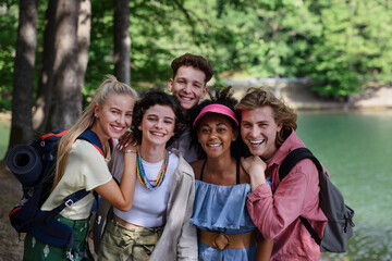 Group of young friends on camping trip near lake in summer.