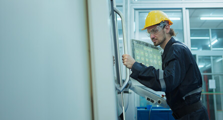 Professional industrial engineer, technician, factory worker wear hard hat, safety glasses while set up, control steelwork machine heavy industry factory. Employee working in manufacturing facility.