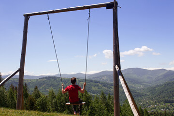 In the mountains of the Ukrainian Carpathians, a guy rides on a swing