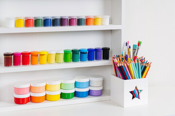 Paints and pencils on white shelves. Stationery and supplies for drawing and craft. Various...