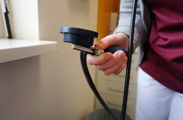 Ärztin misst Blutdruck an Arm von Patientin in Arztpraxis 