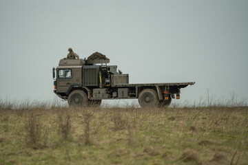 Obraz premium MAN SV 4x4 army logistics vehicle truck driving along a dirt track in action on a military exercise, Wilts UK