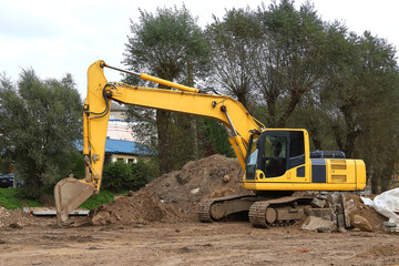 A large construction excavator of yellow color on the city street for quarrying. Industrial concept.