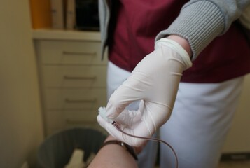 Ärztin mit weißem medizinischem Handschuh entnimmt Blut aus Arm von Patientin in Arztpraxis - obrazy, fototapety, plakaty