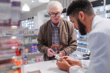 Young pharmacist explaining to customer how to dosing medication.