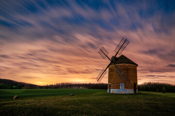 A beautiful Dutch-type windmill in the village of Chvalkovice in South Moravia. Night photograph of windmill with starry sky and reddish light. 