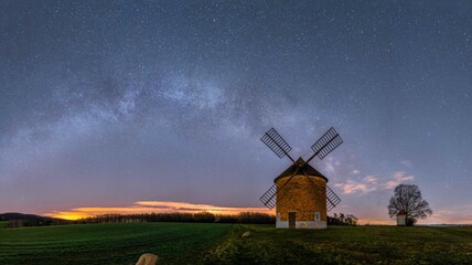 Historic windmill standing in the fields and the night sky with the milky way in the background....