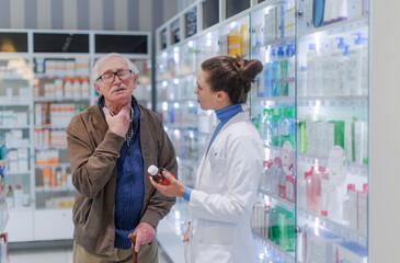 Obraz premium Young pharmacist helping senior man to choos medication.