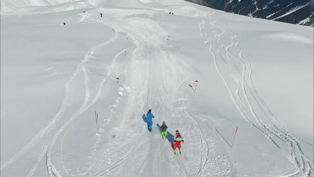 Three people skiing and snowboarding down a slope in the Silvretta Montafon ski area - aerial follow