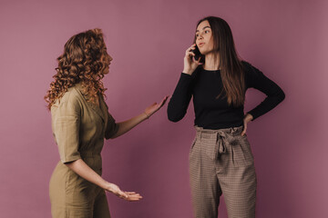 Studio shoot of two young women,one has lon call with mobile phone.