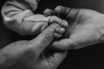 Close-up of parents holding hand of their newborn baby.